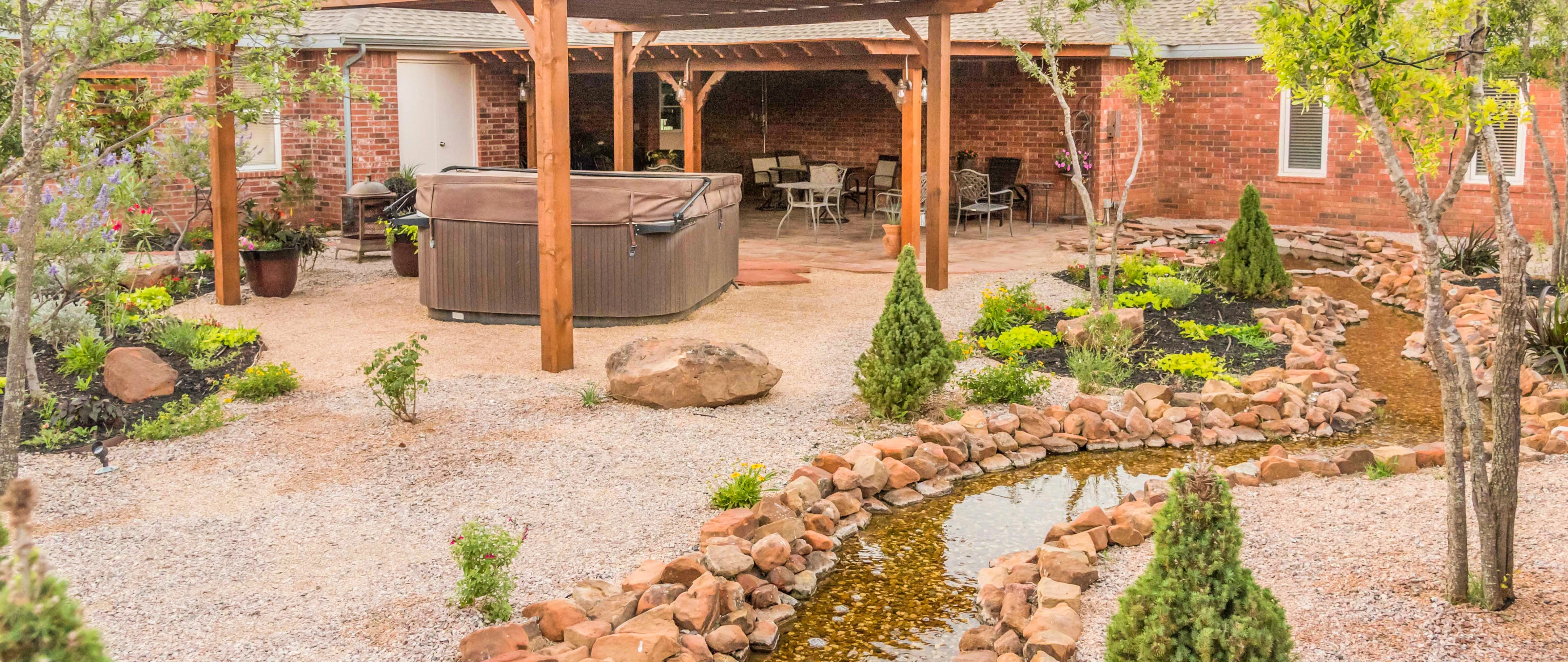 Xeriscape in Lubbock, TX, with dark rocks and small plants.